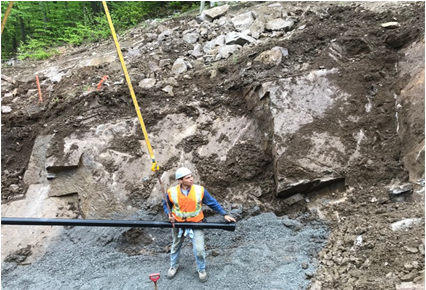 construction worker lowering pipe to ground