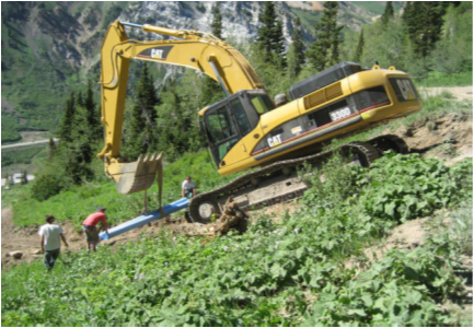 construction vehicle installing pipe on mountain